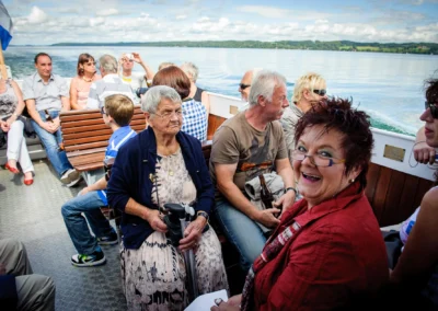 Gäste auf einem Boot bei einer Hochzeit am Starnberger See, lächelnd und entspannt, Hochzeitsfotografie.