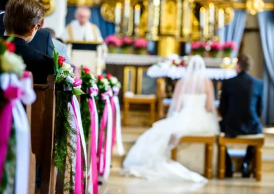 Kirchliche Trauung in Taufkirchen bei Muenchen. Paar kniet vor Altar, Baeume mit Blueten und Bändern dekoriert.