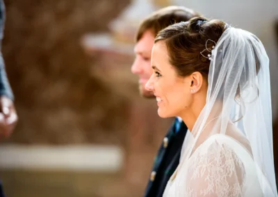 Brautpaar bei kirchlicher Trauung nahe Holzkirchen, Braut in Spitzenkleid und Schleier, aufgenommen von Hochzeitsfotograf.