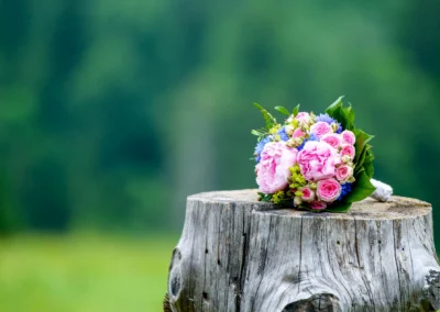 Brautstrauss auf Baumstamm vor unscharfem Hintergrund bei Berg-Hochzeit in Oberbayern. Hochzeitsfotografie im Sillberghaus.