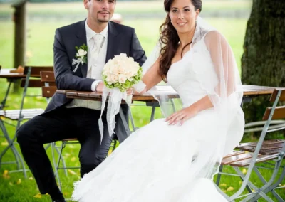Brautpaar auf einer Wiese in Sauerlach-Arget bei der Hochzeitsfotografie, sie mit Blumenstrauss, er im Anzug.