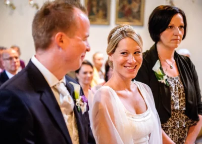 Brautpaar laechelt in der Kirche bei der Trauung in Muenchen, aufgenommen von einem Hochzeitsfotografen.