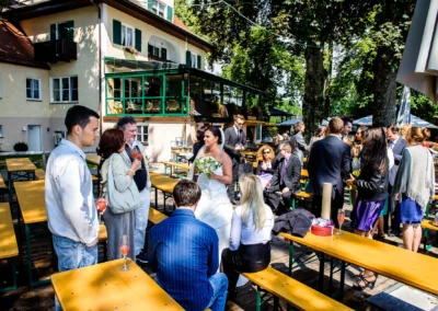 Braut spricht mit Gaesten bei Hochzeitsfeier im Restaurant Alpenblick am Staffelsee. Hochzeitsreportage im Freien.