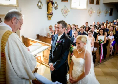 Brautpaar bei kirchlicher Trauung in Taufkirchen, umgeben von Gaesten. Hochzeitsfotograf in der Naehe von Muenchen.