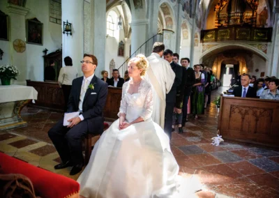 Braut und Braeutigam sitzen in der Kirche bei einer Trauung im Kloster Seeon. Hochzeitsfotografie in Oberbayern.