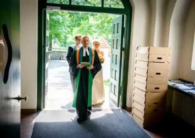 Priester und Paar betreten Kirche zur Trauung, Hochzeitsfotografie in Erlöserkirche Schwabing.