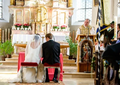 Brautpaar bei kirchlicher Trauung vor Altar in Kirche nahe Holzkirchen. Hochzeitsfotograf fängt feierlichen Moment ein.
