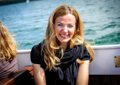 Lachende Frau auf Boot bei Hochzeit am Starnberger See, festgehalten von Hochzeitsfotografie, sonniges Wetter.