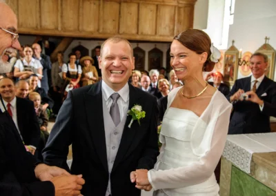 Brautpaar laechelt während kirchlicher Trauung bei Hochzeit auf Gut Thurnsberg nordlich von Muenchen.