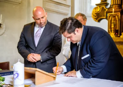 Bräutigam unterschreibt Dokument bei Hochzeit in Kirche in Gmund am Tegernsee. Hochzeitsfotografie in Bayern.
