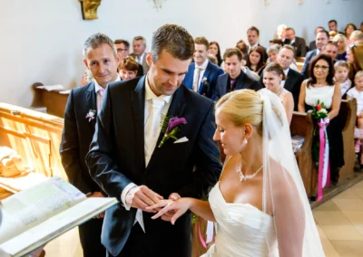 Brautpaar tauscht Ringe bei kirchlicher Trauung in Taufkirchen. Gaeste blicken zu bei Hochzeitsreportage nahe Muenchen.