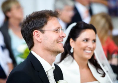 Bräutigam und Braut lächeln während kirchlicher Trauung in Aufkirchen, Hochzeitsreportage nahe Starnberger See.