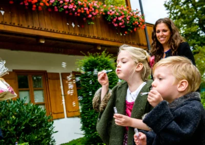 Kinder machen Seifenblasen bei einer Hochzeit nahe Tegernsee. Teil der Hochzeitsreportage eines Fotografen.