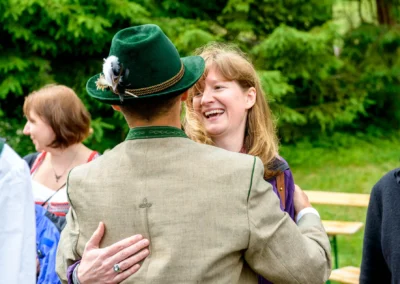 Mann in Tracht und Frau lachend bei Hochzeit im Freien in Bayrischzell. Hochzeitsfotografie im Sillberghaus.
