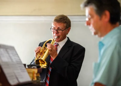 Mann spielt Trompete bei kirchlicher Trauung in Muenchen, festgehalten in einer Hochzeitsreportage.
