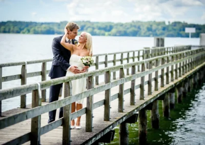 Brautpaar umarmt sich auf Holzsteg am starnberger see. Hochzeitsfotografie bei südlich münchen.