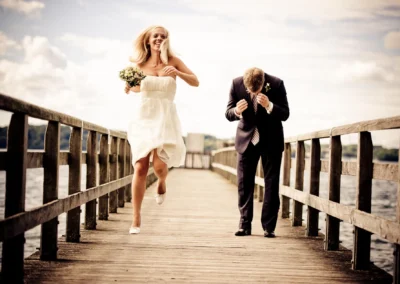 Brautpaar lacht auf einem Steg am Starnberger See, festgehalten bei einer Hochzeitsreportage. Hochzeitsfotografie.