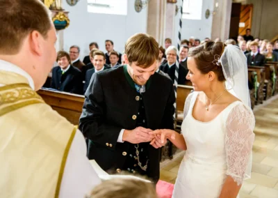 Brautpaar tauscht Ringe bei kirchlicher Trauung nahe Holzkirchen, Trauungsszene von Hochzeitsfotograf in Oberbayern.