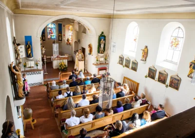 Kirchliche Trauung in Grosshadern: Priester vor Altar, Gaeste in Kirchenbaenken sitzend, Hochzeitsreportage.