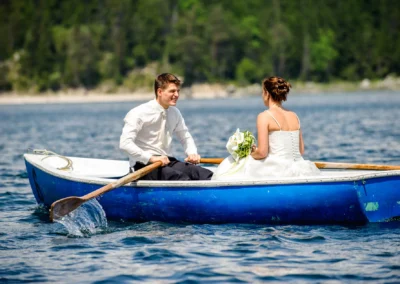 Brautpaar bei Hochzeitsfotografie auf See nahe Eibsee, sitzt im Boot. Hochzeit in malerischer Natur.