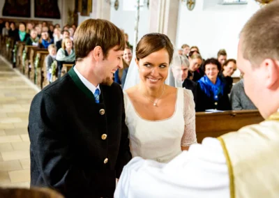 Brautpaar laechelt einander in Kirche bei der Trauung in Valley an. Hochzeitsfotografie in Oberbayern.