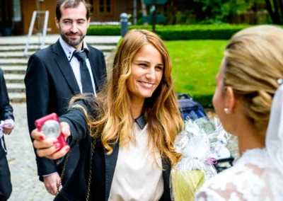 Lachende Frau ueberreicht Geschenk an Braut bei Hochzeit in Waakirchen. Hochzeitsreportage zeigt freudige Gesichter.