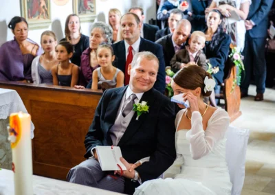 Brautpaar sitzend in Kirche, Trauung bei Hochzeit, Gaeste im Hintergrund, bei Freising fotografiert.