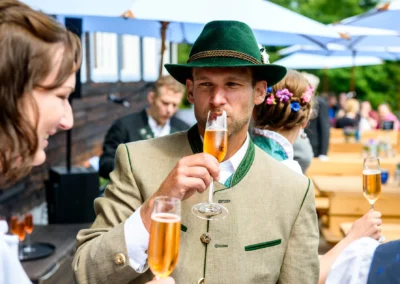 Mann in Tracht trinkt Champagner bei Hochzeit im Sillberghaus, Oberbayern. Hochzeitsreportage von Hochzeitsfotograf.