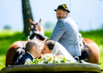 Brautpaar bei Hochzeitsfotografie im Kutschwagen in Uffing am Staffelsee, fotografiert waehrend romantischer Moment.