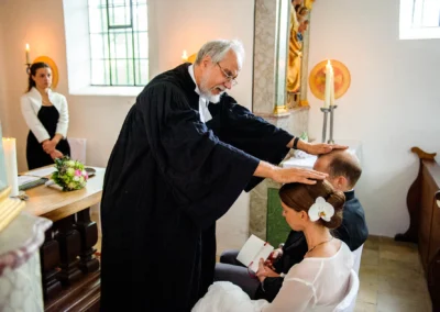 Pfarrer segnet Brautpaar waehrend kirchlicher Trauung in der Kapelle, Hochzeitsfoto bei Freising.