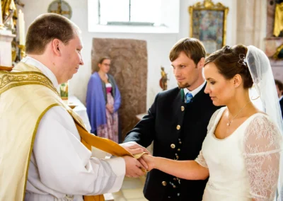 Brautpaar und Pfarrer bei kirchlicher Trauung in Valley. Hochzeitsfotograf fängt Ringe-Austausch ein.
