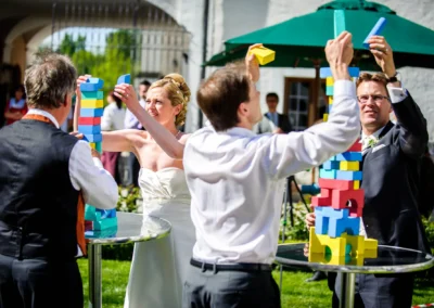Braut und Gaeste spielen mit Bauklötzen bei Hochzeit im Kloster Seeon im Chiemgau, Hochzeitsreportage im Freien.