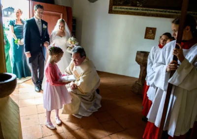 Brautpaar und Blumenmädchen bei kirchlicher Trauung in Schaftlach, begleitet von Priester und Ministranten. Hochzeitsfoto.