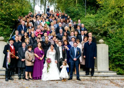 Gruppenfoto bei kirchlicher Trauung in Gilching, Brautpaar mit Familie und Freunden auf Treppe, Hochzeitserinnerung.