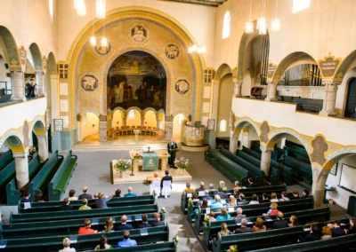 Kirchliche Trauung in Schwabing mit Blick auf die geschmueckte Kirche und Gaeste bei der Hochzeitsfotografie.