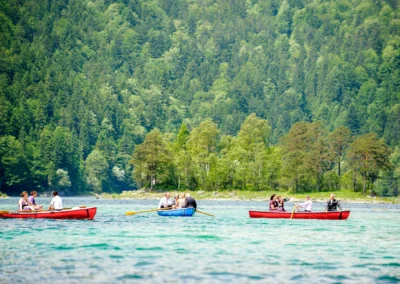 Hochzeitsfoto: Boote mit Hochzeitsgaesten auf dem Eibsee, gruenes Waldpanorama im Hintergrund. Hochzeitsreportage.
