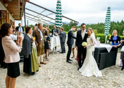 Brautpaar mit Gaesten im Freien bei einer Hochzeit nahe Tegernsee, alle in festlicher Kleidung, Hochzeitsreportage.