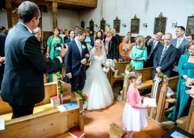 Brautpaar schreitet durch Kirche in Schaftlach, gefolgt von Gästen. Kirchliche Trauung bei einer Hochzeit.