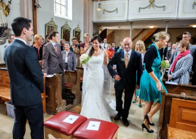 Braut mit Blumenstrauss bei kirchlicher Trauung in Pfarrkirche Sankt Michael. Festlicher Moment der Hochzeitsreportage.
