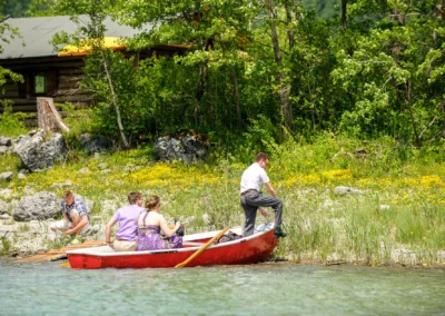 Hochzeitsreportage am Ufer des Eibsees mit einem roten Boot und Personen bei sonnigem Wetter.