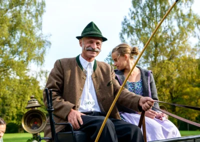 Mann in traditioneller Tracht und Frau in Dirndl auf Kutsche bei Hochzeit im Leitzachtal, Herbst.