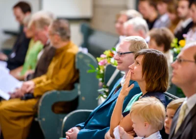 Gäste sitzen in einer Kirche in München Schwabing während einer Hochzeitsreportage. Emotionen bei der Trauung.