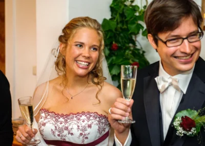 Brautpaar hebt Champagnergläser bei Hochzeit in Strandcafe Bucherer, festgehalten von Hochzeitsfotografie.