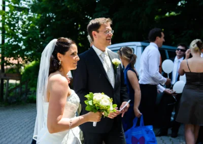 Braut und Bräutigam bei ihrer Hochzeit im Freien auf der Sprengenöder Alm, begleitet von Gästen mit Luftballons.