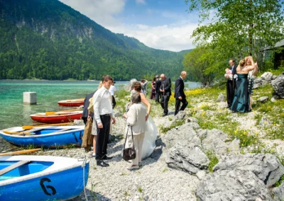 Hochzeitsfoto am Eibsee: Gäste am Ufer mit Booten, Bergen im Hintergrund, Hochzeit bei Garmisch