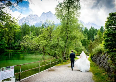 Brautpaar spaziert am Badersee bei Hochzeit unter Bergen, Hochzeitsreportage nahe Zugspitze im Kreis Garmisch-Partenkirchen.