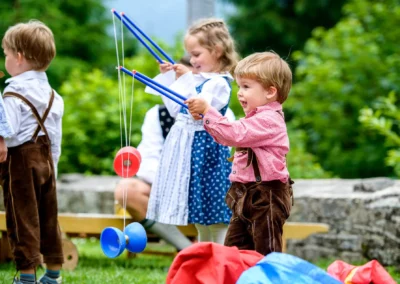 Kinder spielen auf einer Hochzeit im Sillberghaus, bayrisch gekleidet mit traditioneller Tracht im Freien. Hochzeitsfotografie Oberbayern.