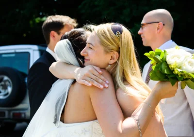 Braut und Gast umarmen sich bei Hochzeit auf Sprengoeder Alm, feiern in Oberbayern nahe Starnberger See. Hochzeitsfotografie eingefangen.