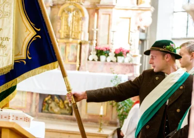 Mann bei kirchlicher Trauung mit Fahne im Kleid mit Tracht. Hochzeit in Valley nahe Holzkirchen, Fotografie.