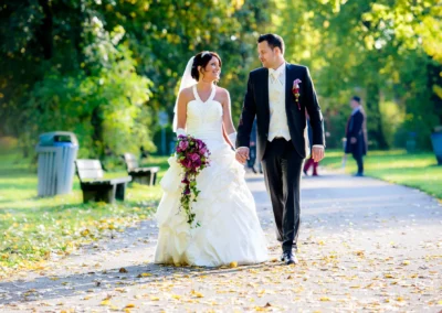Brautpaar geht Hand in Hand in einem Park in Karlsfeld. Hochzeitsfotografie, romantische Hochzeitsportraits.